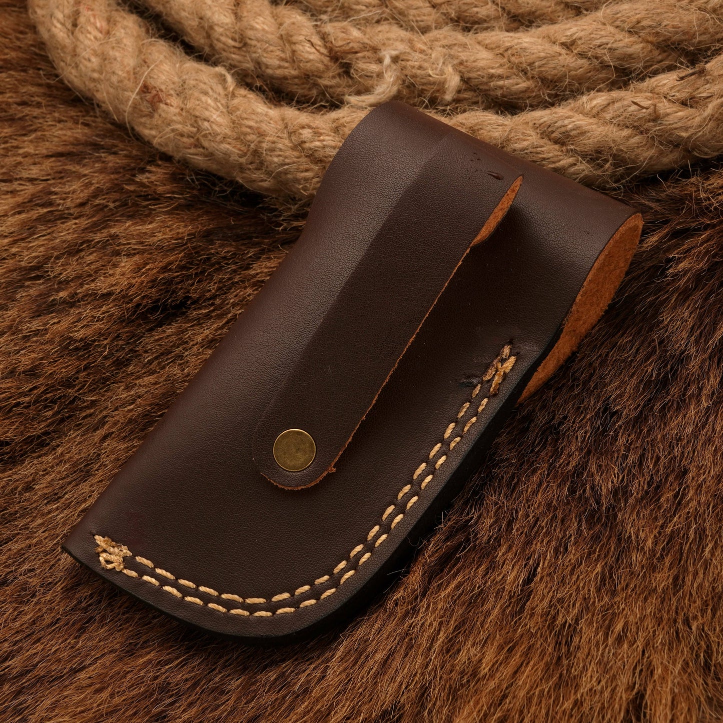 Back view of a brown leather sheath with stitched detailing, crafted to fit a Damascus pocket knife for safe storage and transport.