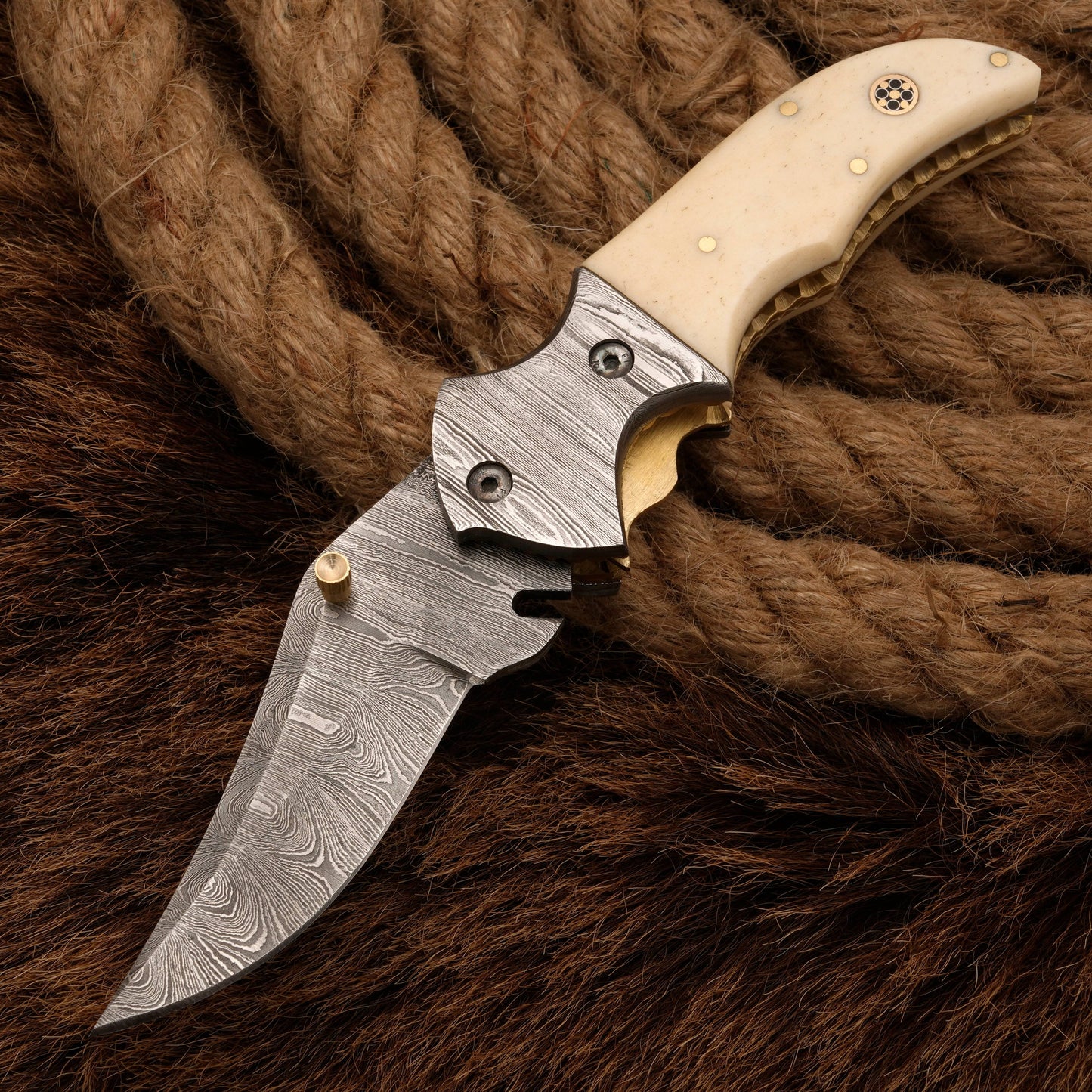 Custom hand-forged Damascus pocket knife with a bone handle, featuring a Damascus bolster and intricate blade patterns, displayed on a rustic background.