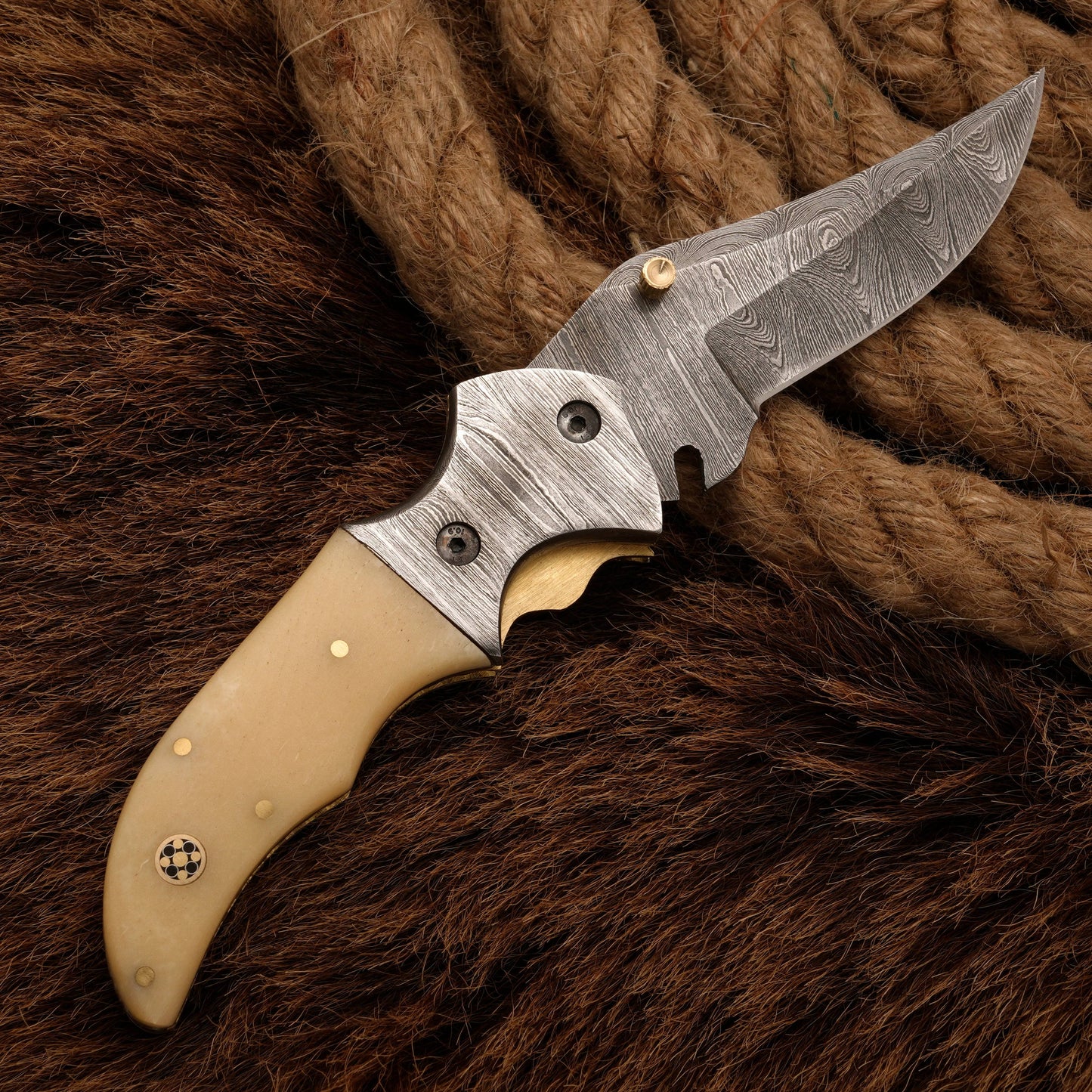 Hand-forged Damascus folding knife with a bone handle and a sharp patterned blade, perfect for outdoor enthusiasts and collectors.