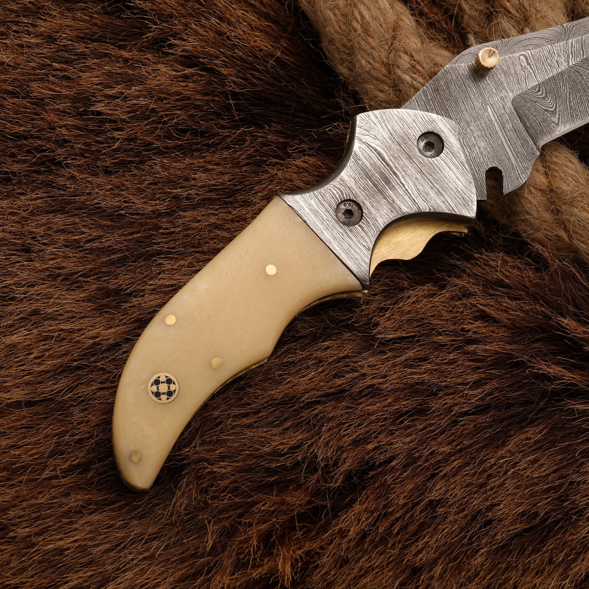 Bone handle of a custom Damascus pocket knife, featuring brass accents and a detailed bolster for a premium look.