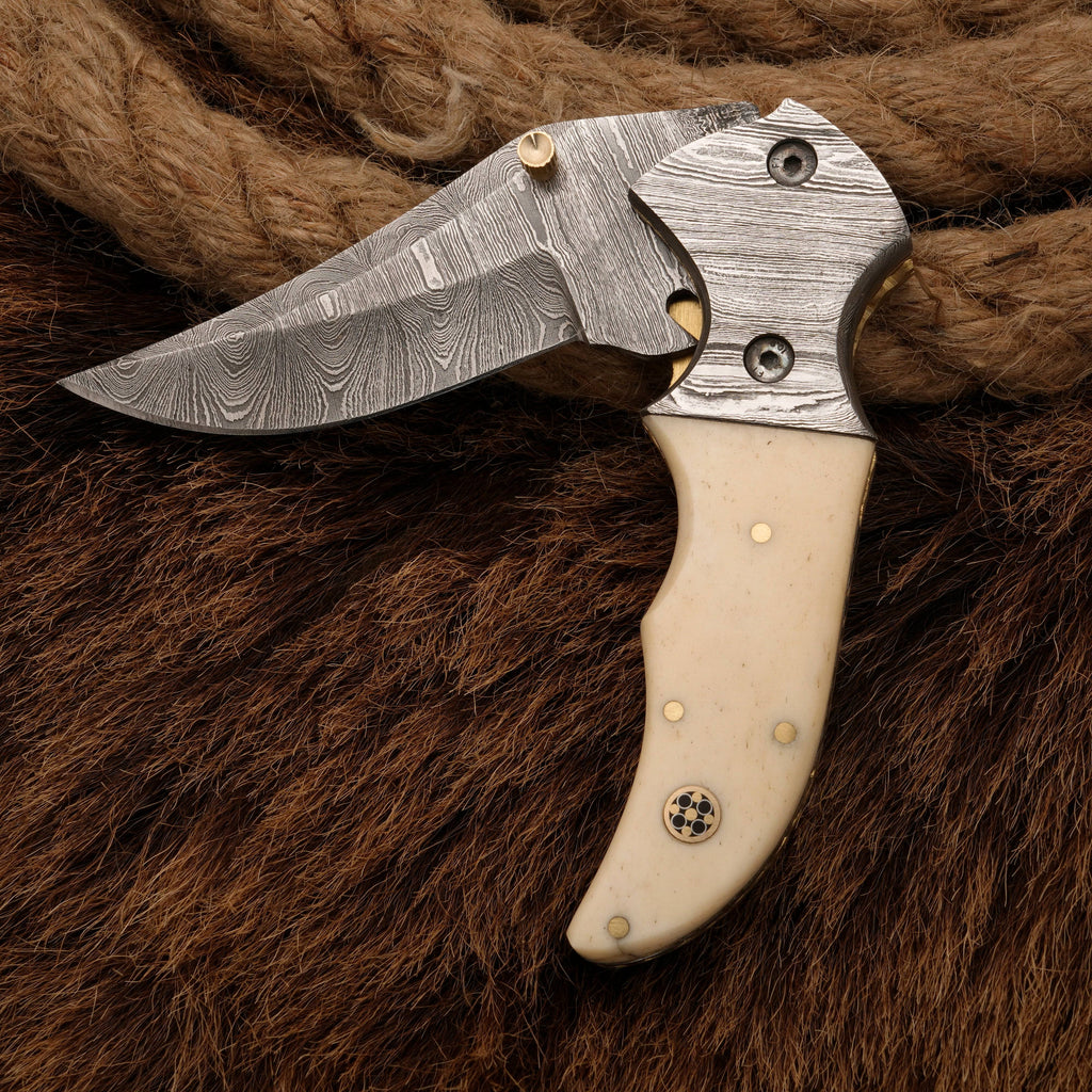 Folding Damascus pocket knife with a bone handle and detailed bolster, showcasing its elegant craftsmanship and sharp blade design.