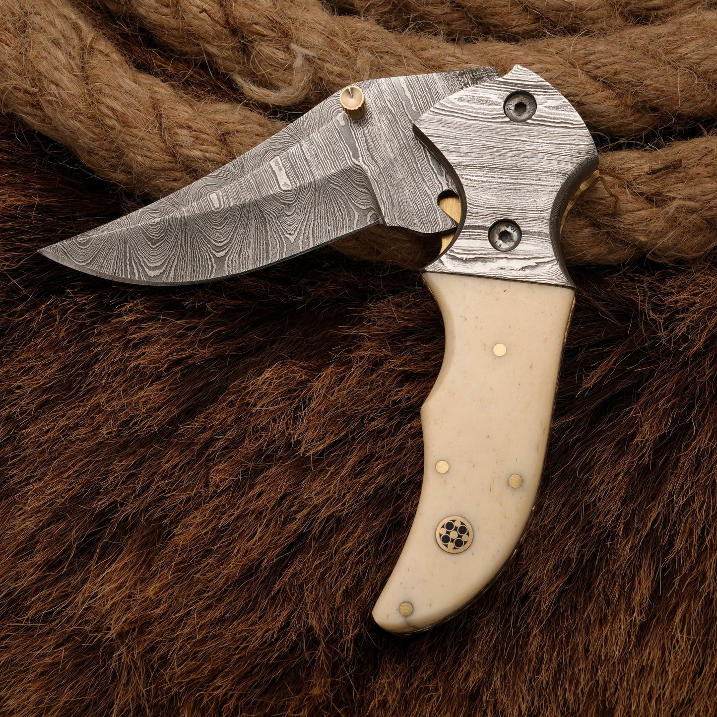 Folding Damascus pocket knife with a bone handle and detailed bolster, showcasing its elegant craftsmanship and sharp blade design.