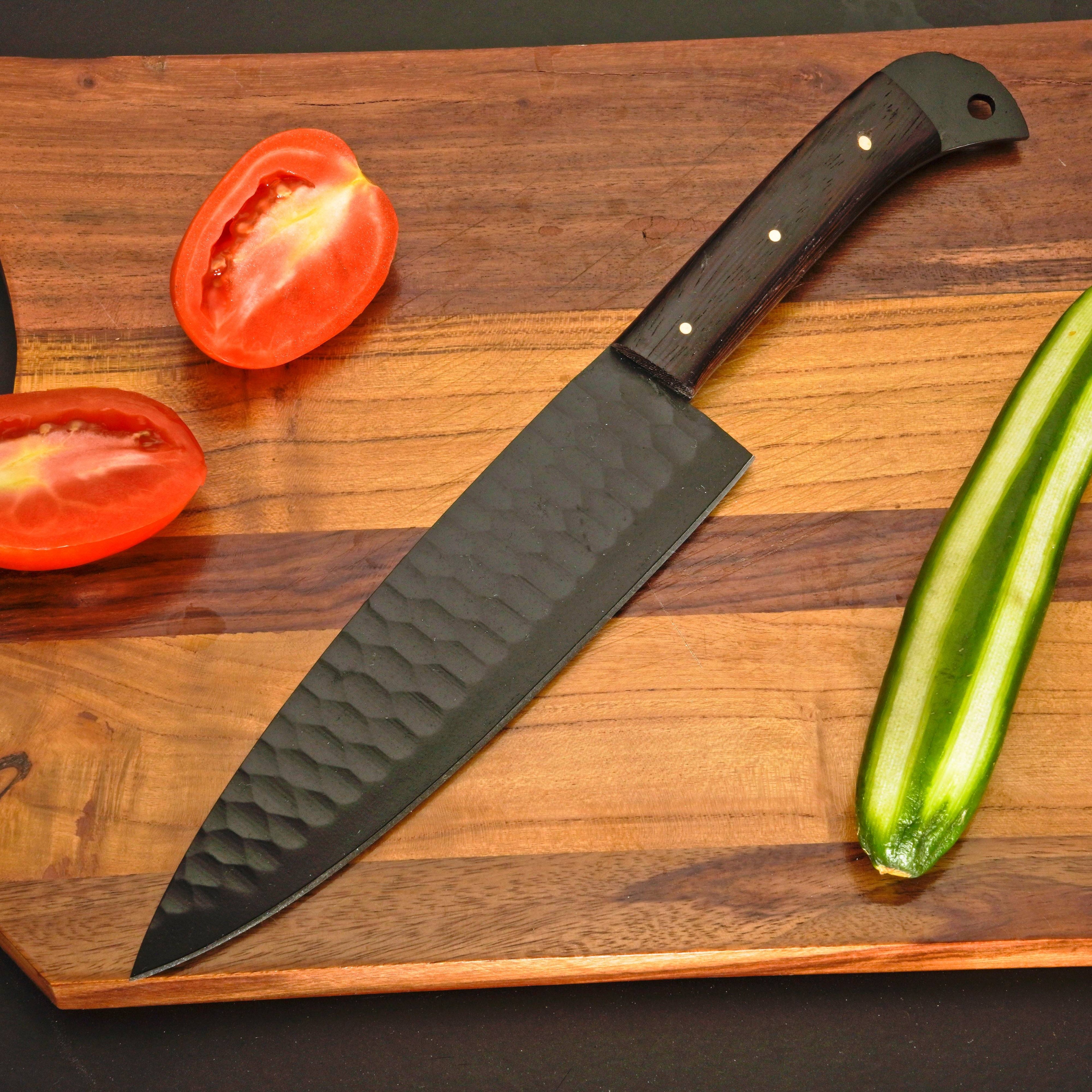 Chef's knife on a wooden cutting board with tomatoes and a cucumber