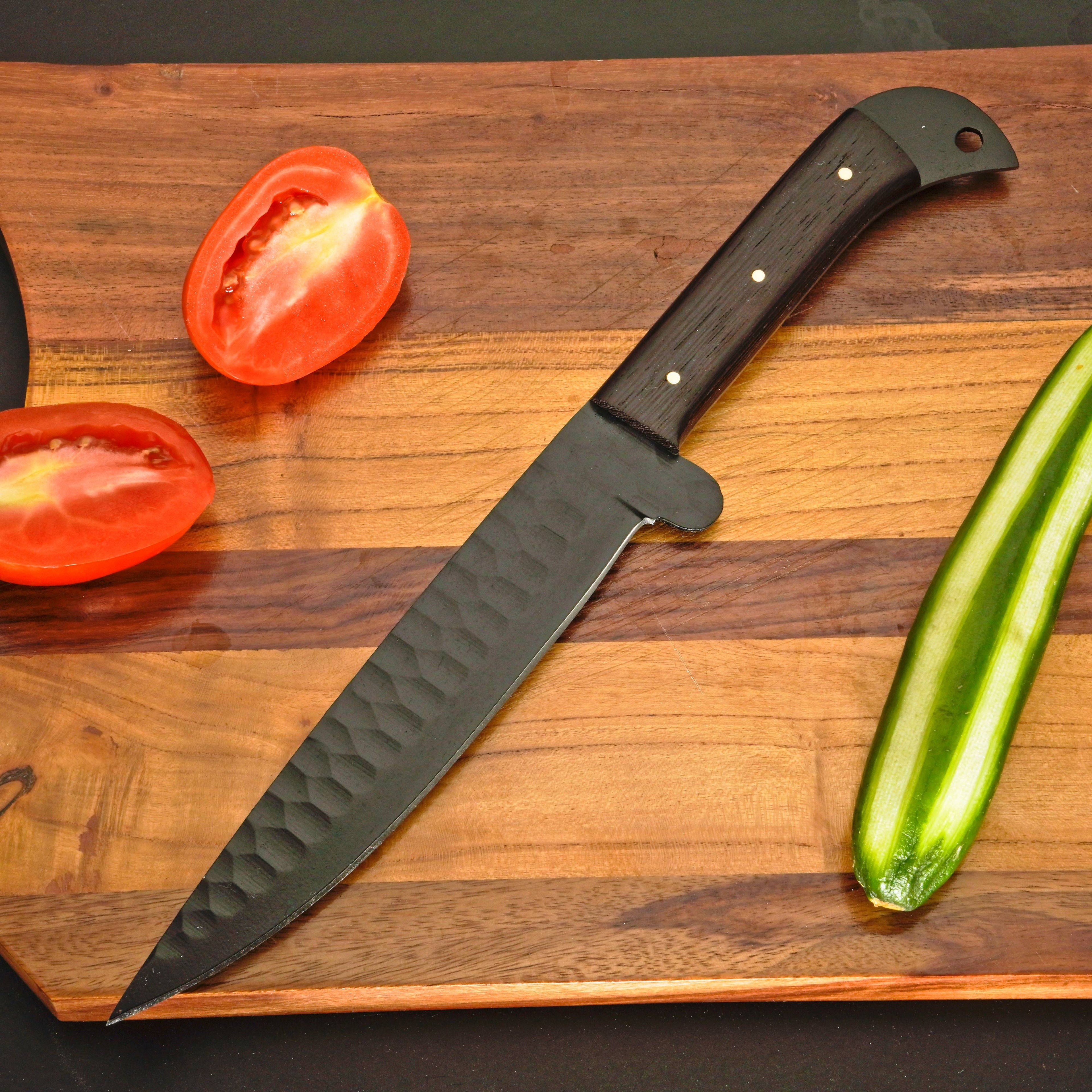 Large knife with a wooden handle on a wooden cutting board with sliced tomatoes and a cucumber.
