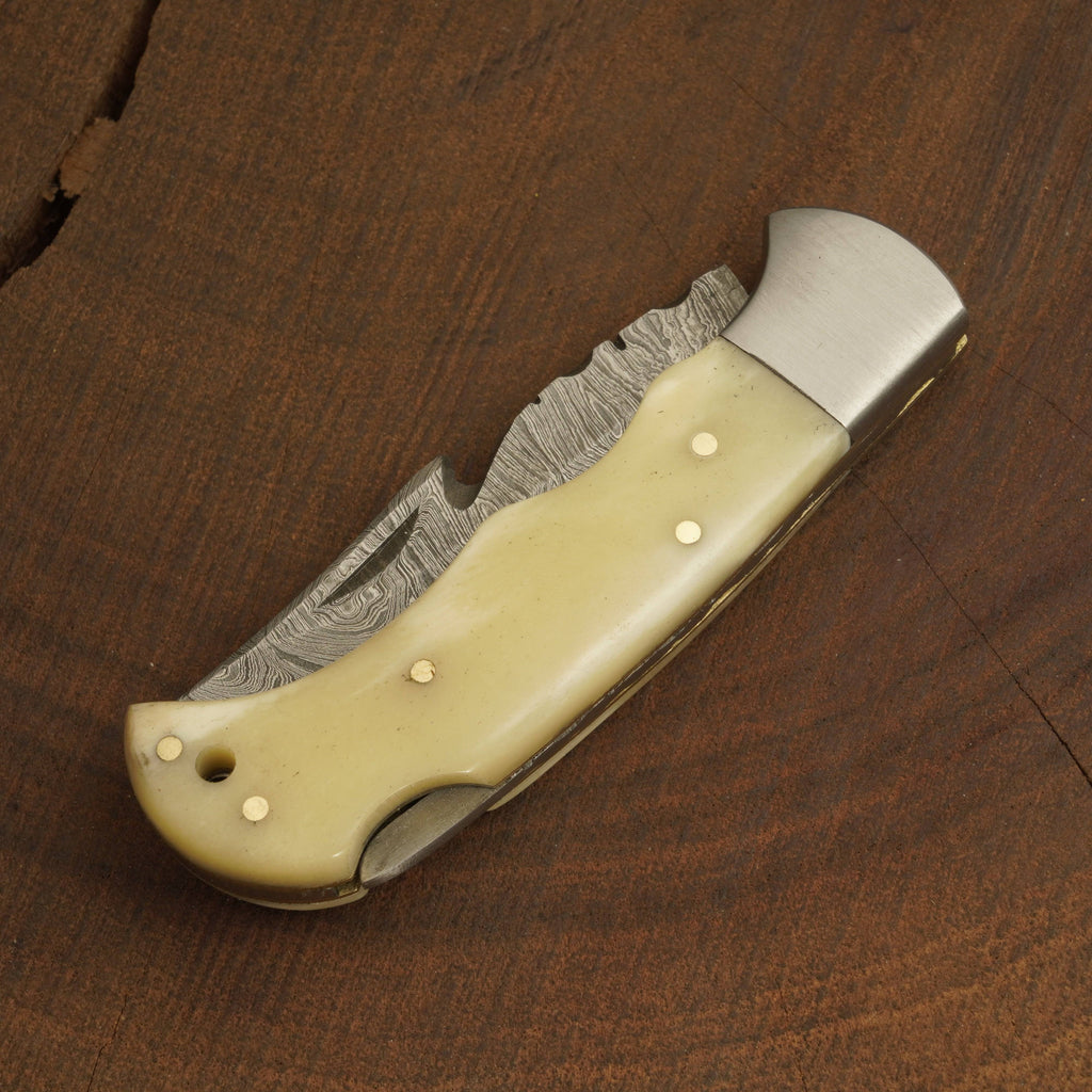 Folding knife with a beige handle on a wooden surface