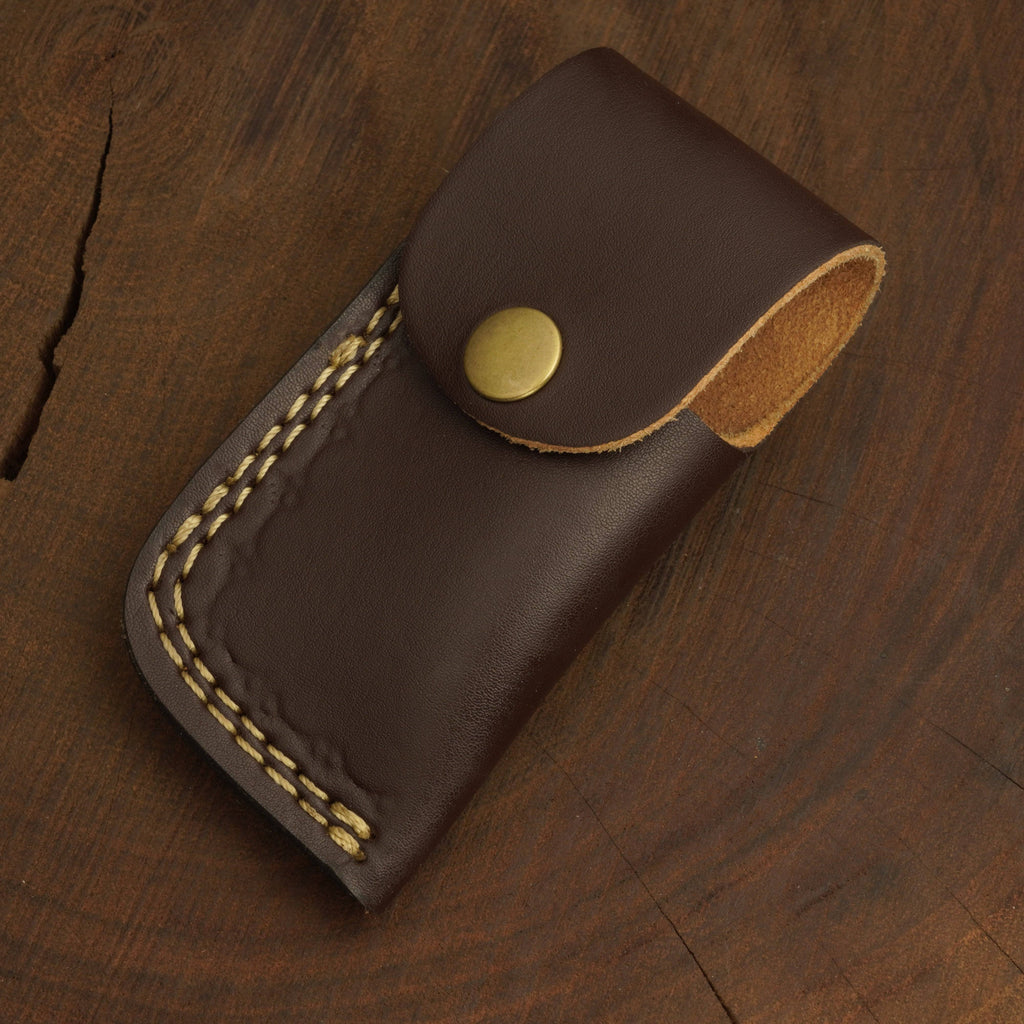 Brown leather pouch with gold stitching and button on a wooden surface