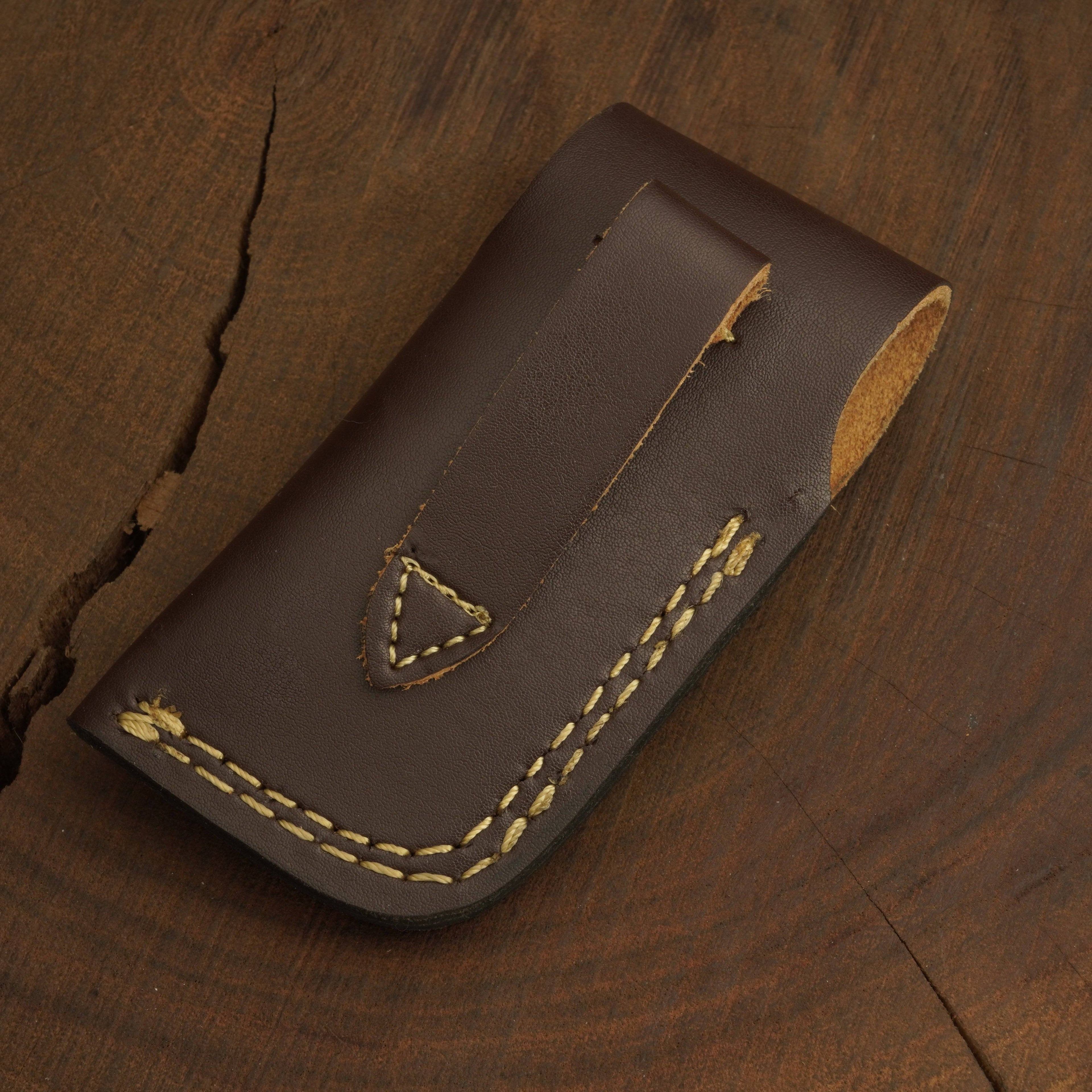 Brown leather pouch with yellow stitching on a wooden surface